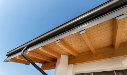 How can checking roof overhangs help protect walls from heavy rain