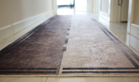 How can placing runners in busy corridors protect flooring underneath