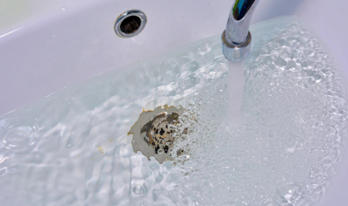 Why is it unwise to ignore a slow-draining shower or basin